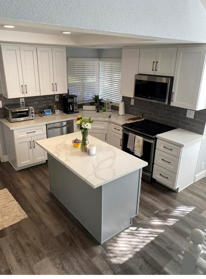 Completed two-tone kitchen with white shaker perimeter cabinets and a gray island