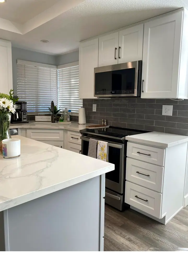 Completed two-tone kitchen with white shaker perimeter cabinets and a gray island