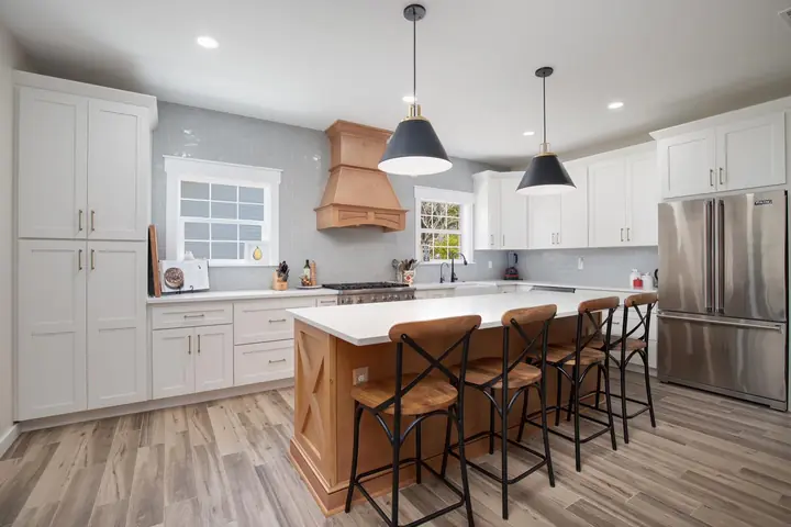 Completed white shaker kitchen with a custom wood range hood and wood-top island