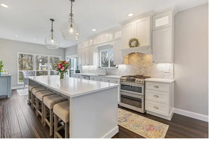 Completed white shaker kitchen with a large quartz island and arabesque marble backsplash