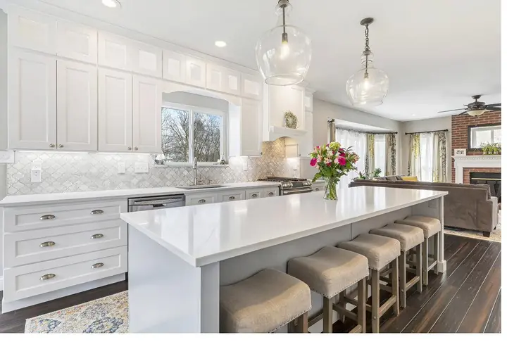 Completed white shaker kitchen with a large quartz island and arabesque marble backsplash
